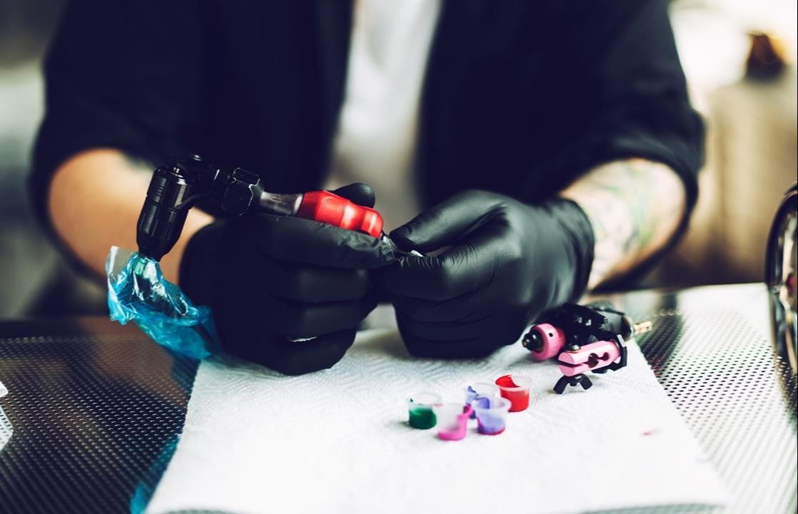 mężczyzna przygotowuje urządzenie do tatuażu na kurs tatuażu
