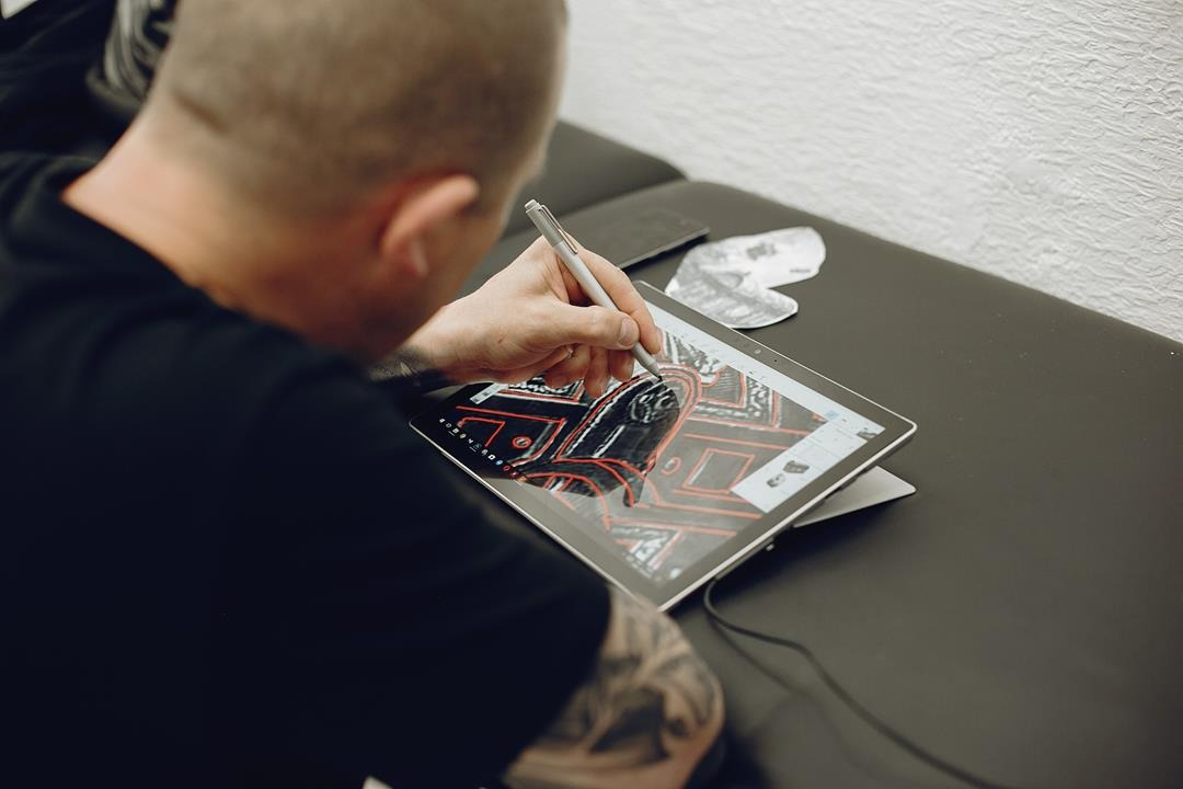 mężczyzna wykonuje projekt tatuażu na tablecie przy użyciu AI