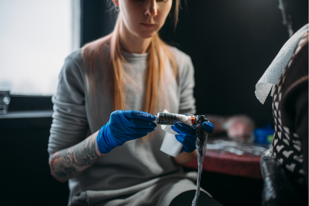 tatuatorka przygotowuje stanowisko tatuatorskie do sesji tatuażu