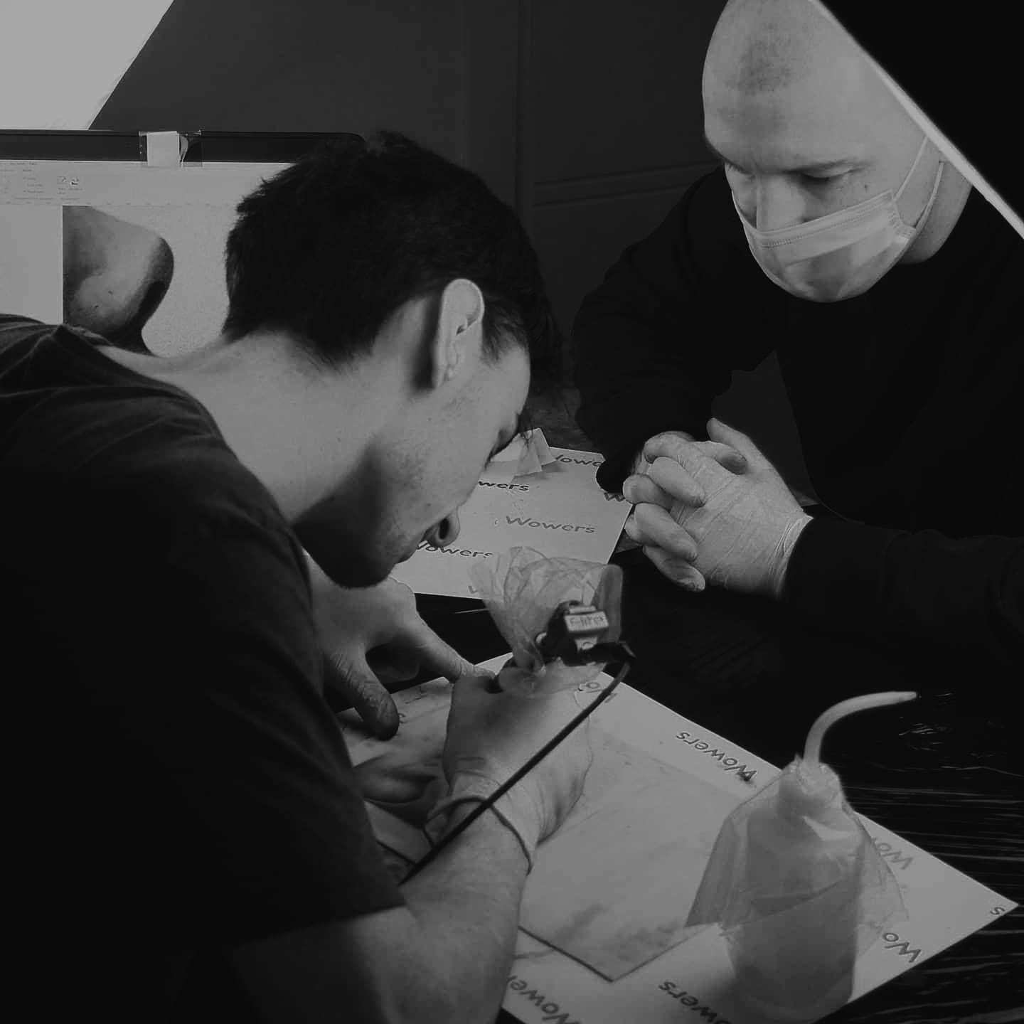 Maciej pracujący z kursantem podczas tatuowania w studio tatuażu