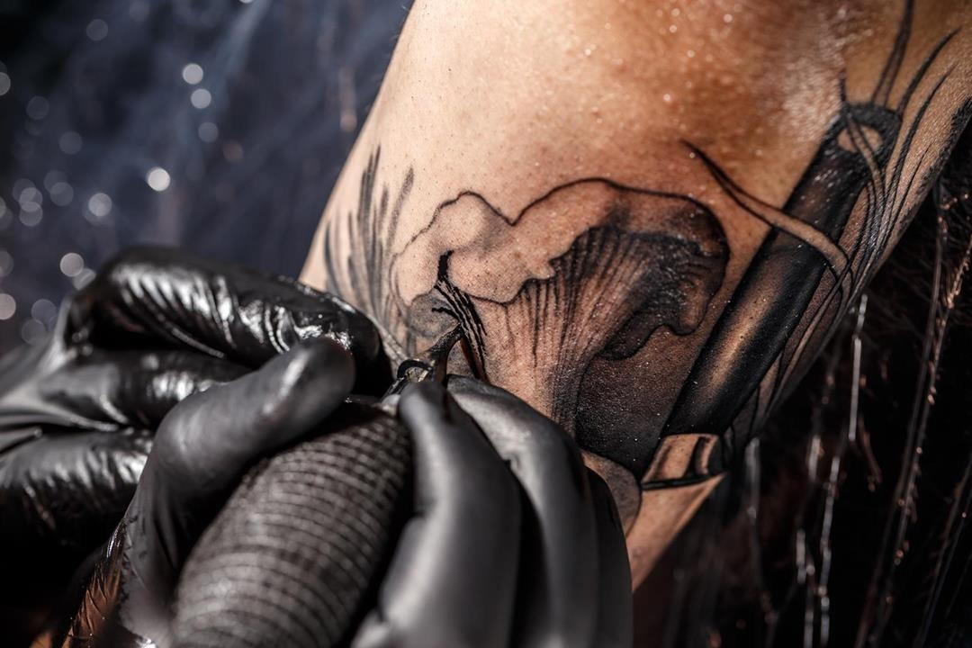 tatuator wykonuje tatuaż na przedramieniu