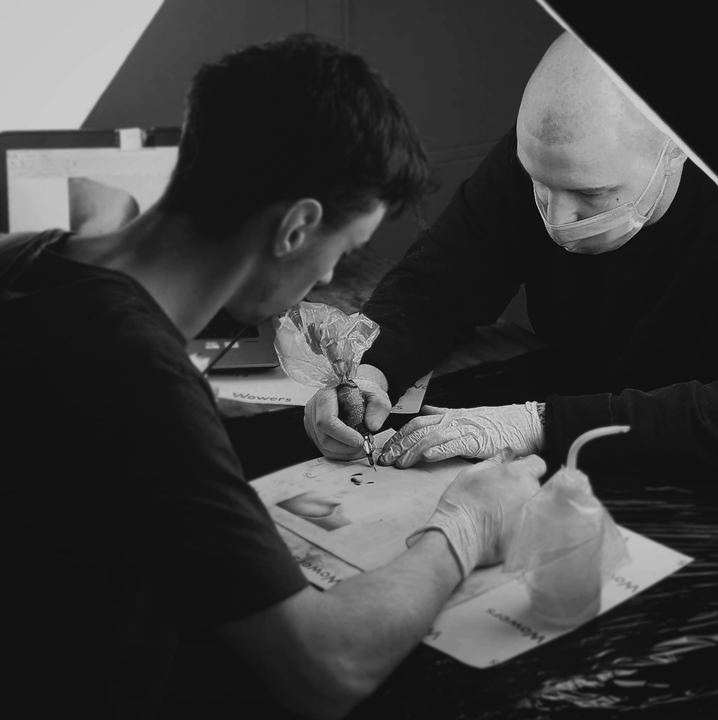 dwóch mężczyzn wykonują kurs tatuażu na sztucznej skórze